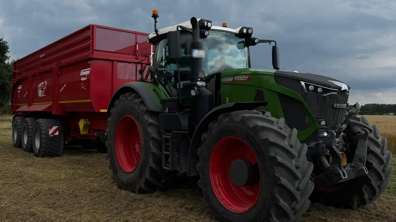 Fendt-Traktor mit rotem Kippanhänger auf einem abgeernteten Feld